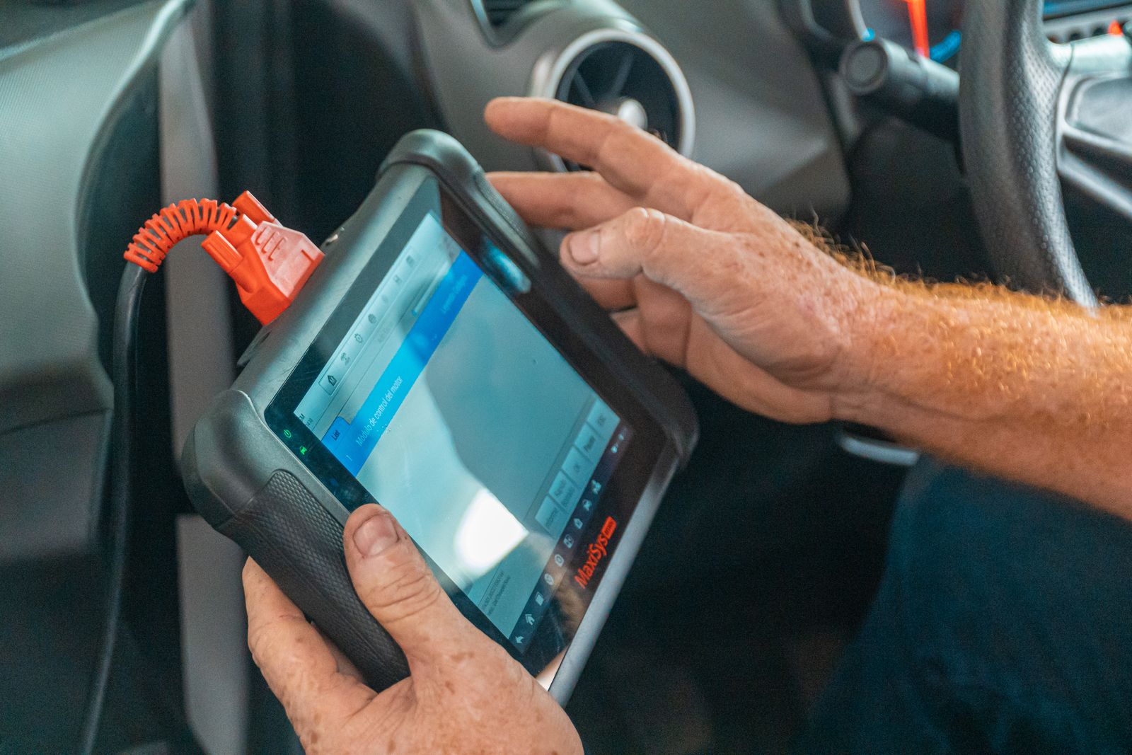 Mobile technician using a diagnostic scan tool at a car in Watford